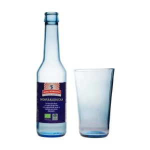 Frilagd bild på stapelbart glas i ljusblått glas, tillsammans med flaskan det är tillverkat av